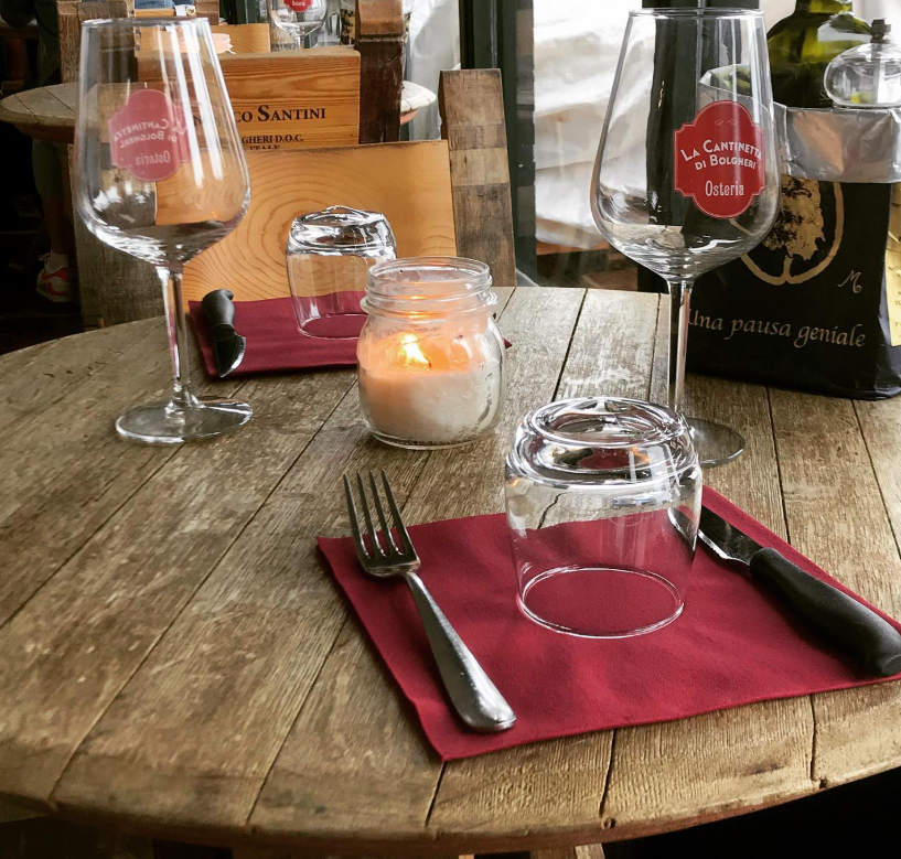 Tavolo apparecchiato della Cantinetta di Bolgheri con calici e candela